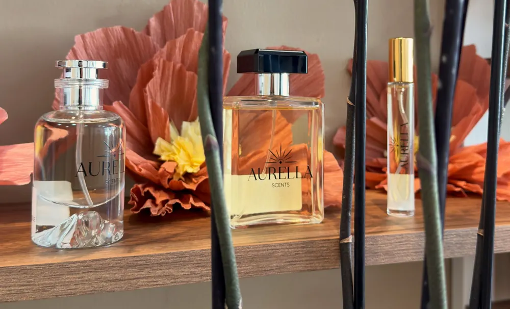Frascos Aurella de 50, 100 y 10 ml en una repisa, entre orquídeas