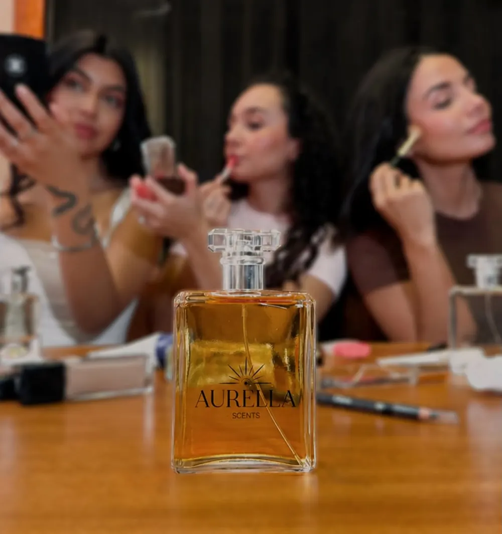 Frasco Aurella sobre una mesa de maquillaje, con tres amigas detrás